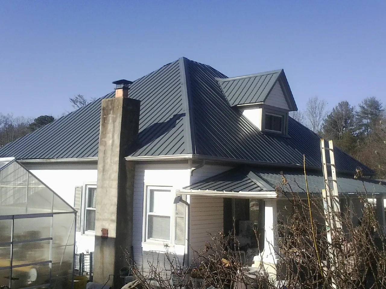 Dark blue standing seam metal roof on a white farmhouse with dormer — Slate & Tile Roof Repair by Roofing Brothers in Faith