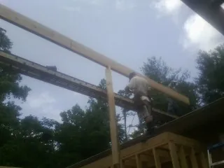 Carpenter setting a ridge beam over a new addition frame — Ice Dam Removal by Roofing Brothers in Faith