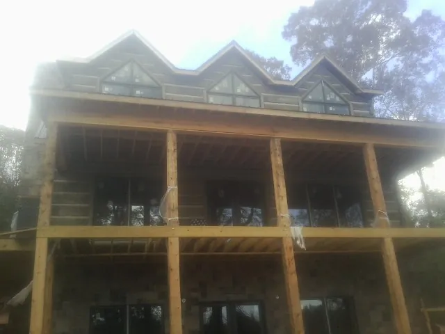 Dormers and porch framing on a large log home under construction — Roof Coating work by our crew in Faith