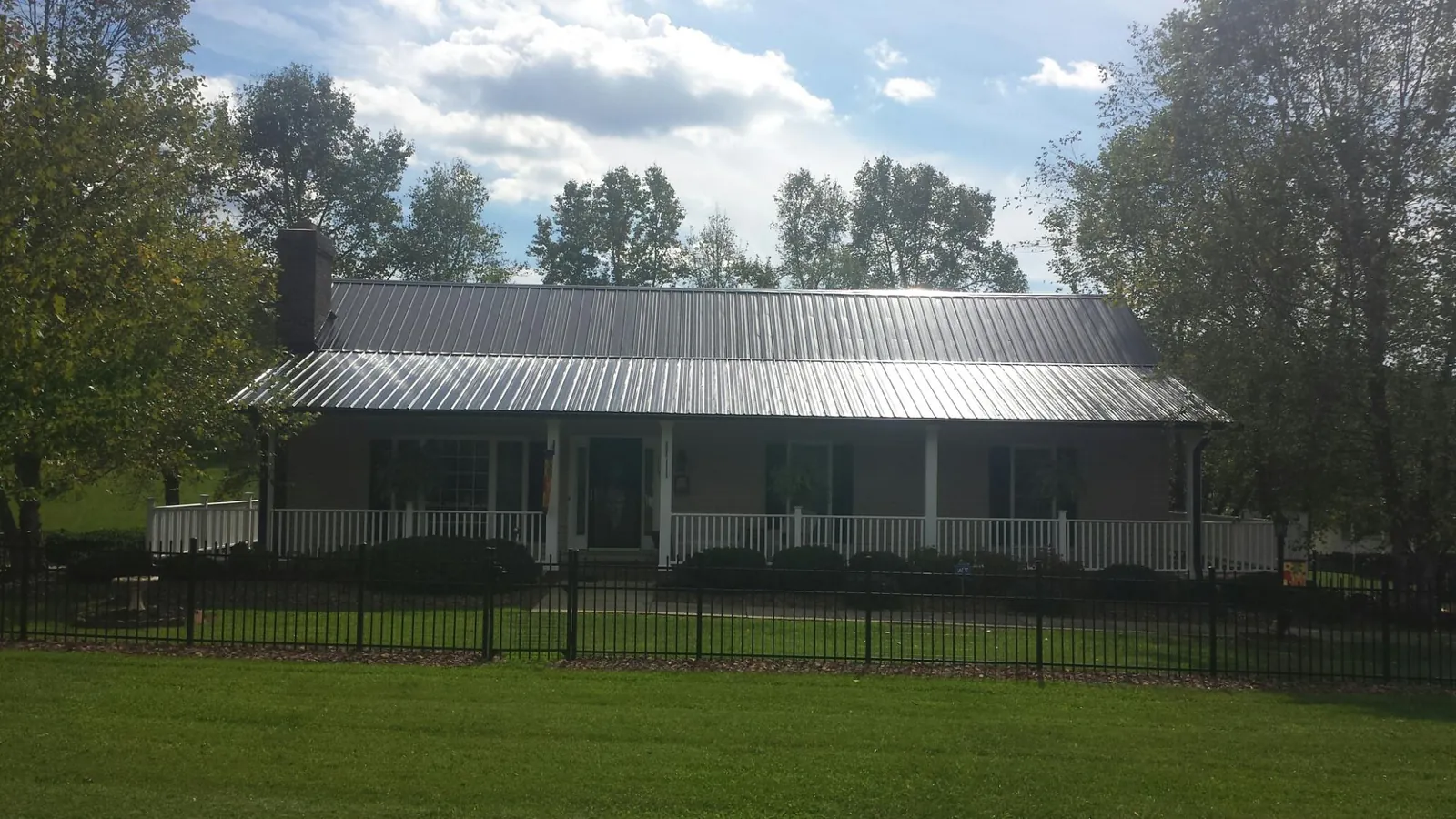Gray metal roof on a brick ranch with a full width front porch — Gutter Guard Installation work by our crew in Faith