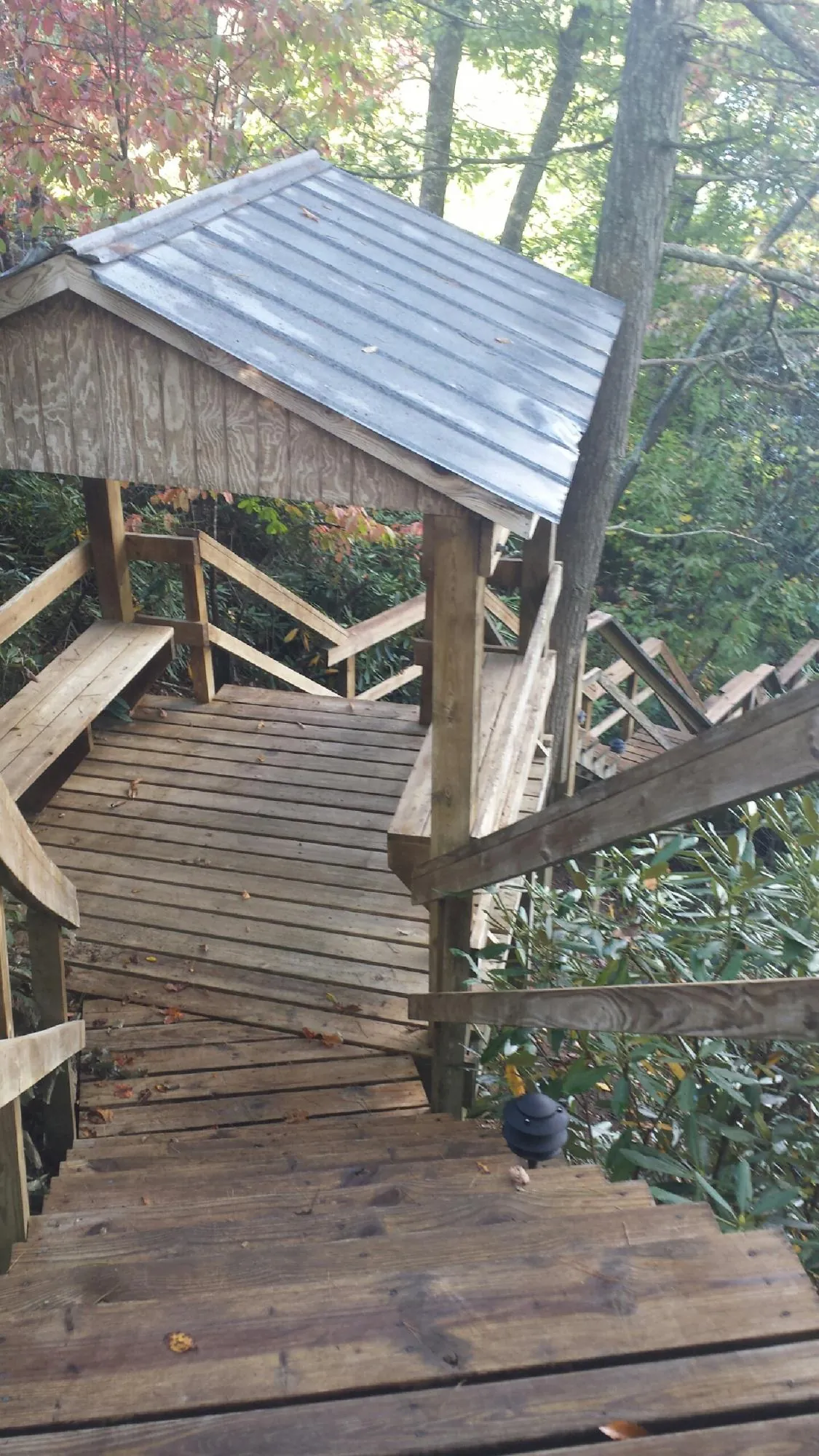 Metal roofed shelter over wooden steps on a wooded walkway — Skylight Repair & Installation work by our crew in Faith