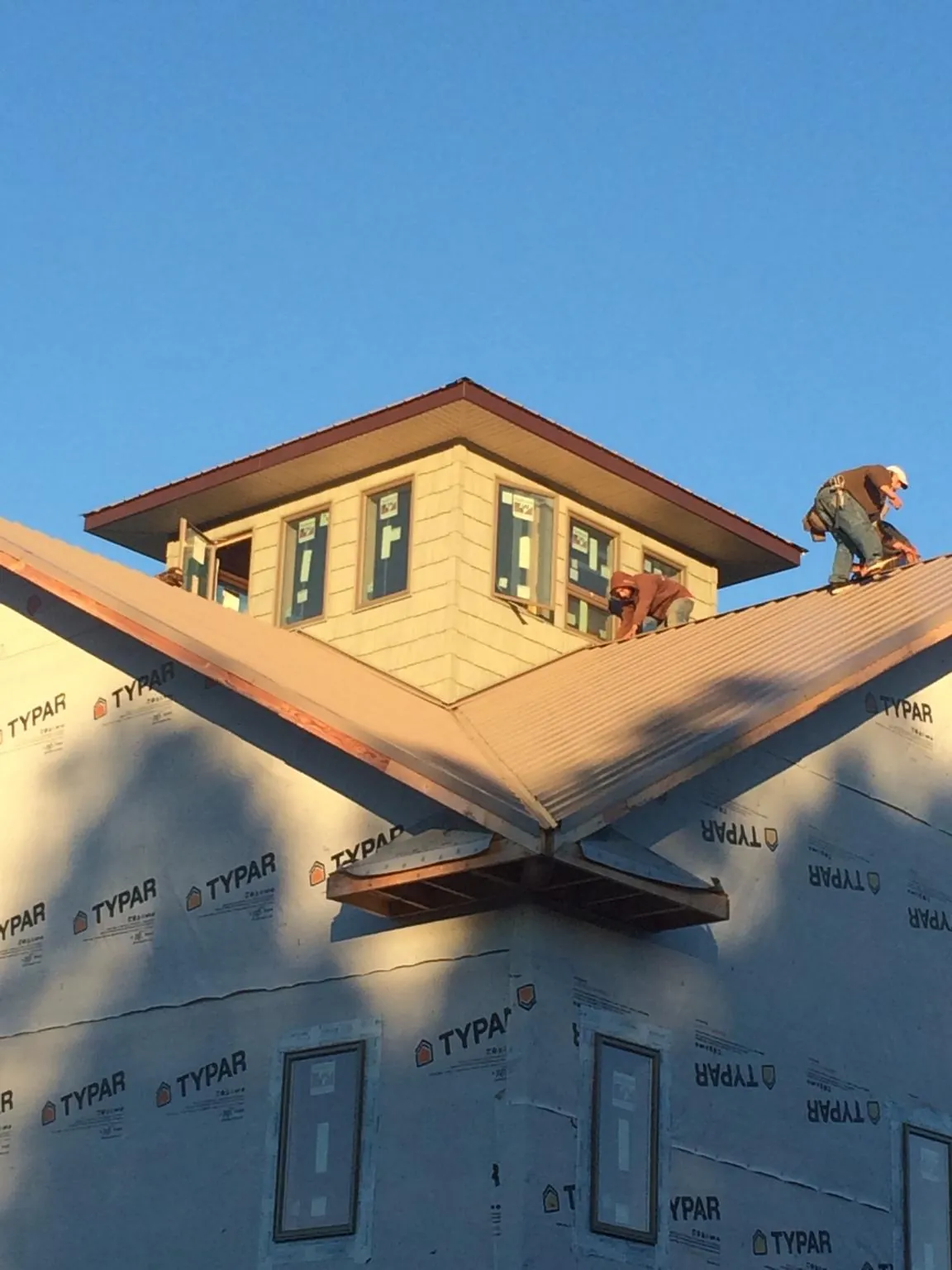 Roofers working around a rooftop cupola on a new metal roof at sunset — Roof Waterproofing in Faith by Roofing Brothers